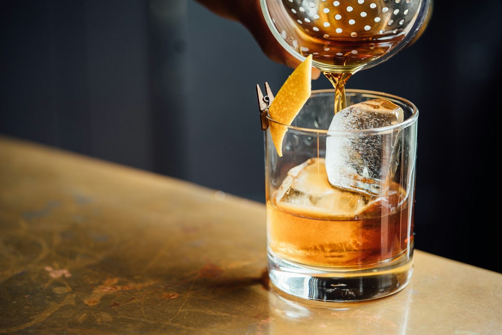 A bartender shaking a cocktail in a steel shaker under warm low light