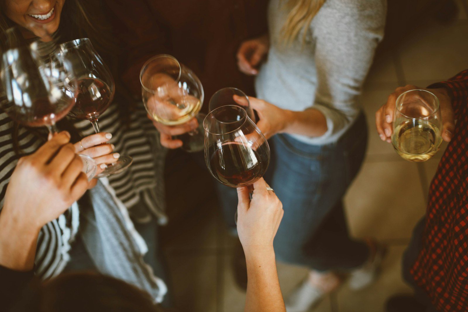 A group of guests reaching in together to clink their glasses in warm low light